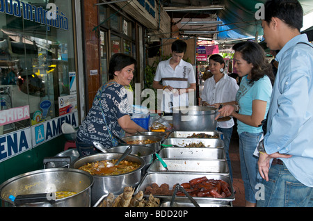 Bangkok Thais choosing hot fiery curries for their lunch from a mobile street kitchen Stock Photo