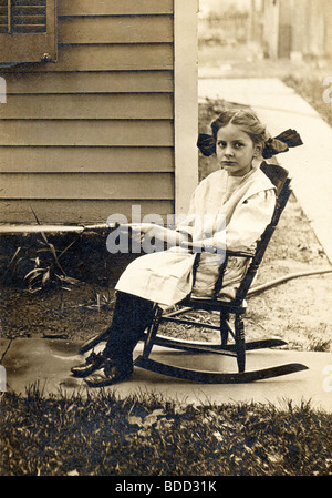 Little Girl Watering Garden from Rocking Chair Stock Photo