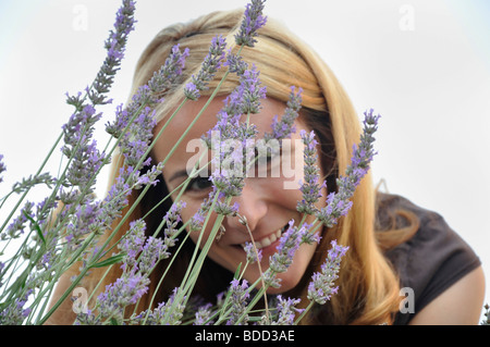 Young woman smiling hiding behind bunch of lavender flowers Stock Photo