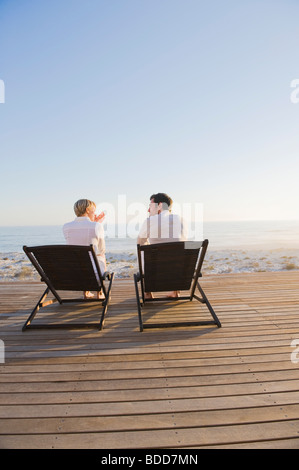Couple sitting on deck chairs on the beach Stock Photo