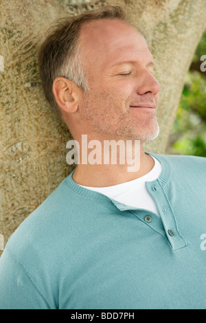 Man leaning against a tree trunk Stock Photo
