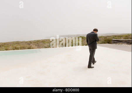 Rear view of a businessman walking at the poolside Stock Photo