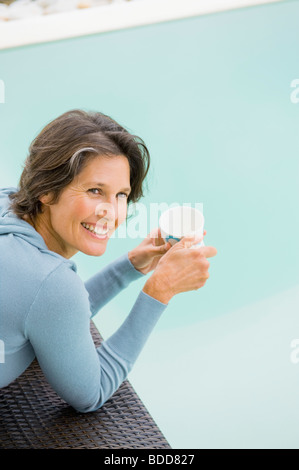 Woman drinking tea at the poolside Stock Photo