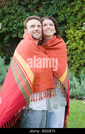 Couple wrapped in a shawl and smiling Stock Photo