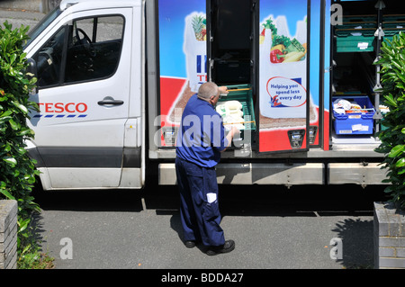 Tesco supermarket home delivery business van open side of groceries in food crates & staff man driver unloading online grocery shopping England UK Stock Photo