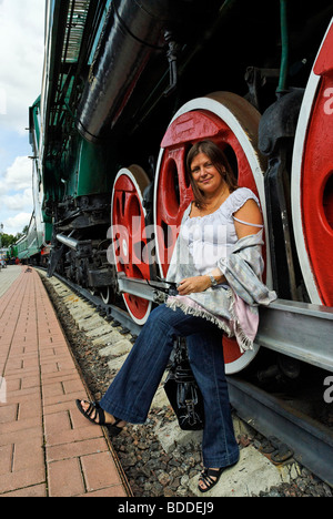 A woman stays close to giant wheel of height 1850 mm of the Soviet steam locomotive P36-0001. Built in 1950. Stock Photo