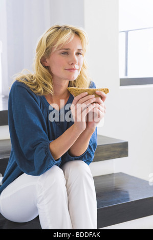 Woman sitting on steps and holding a sandwich Stock Photo