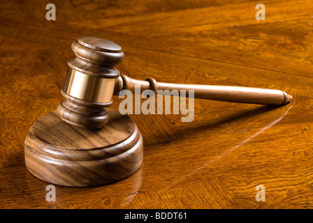 An elegant gavel and block on an deep, richly colored wooden desk. Stock Photo