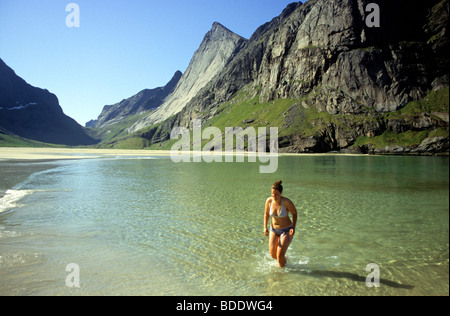 A young woman swims in the Icy Arctic waters of Horseid bay on Moskensoya Islands western wilderness. Lofoten, Norway. Stock Photo