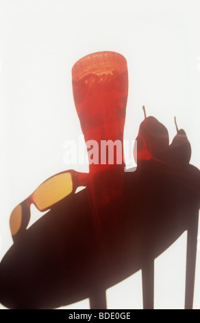 Shadow on white textured wall of circular table with red glass tumbler brown sunglasses and two pears Stock Photo