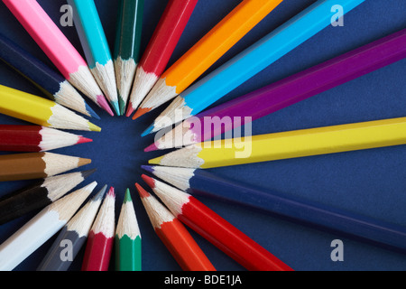 Ring of coloured pencils on blue background - looking down on from above Stock Photo