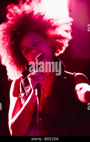 young woman singing into microphone Stock Photo