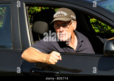 Portrait of an angry motorist making hand signs from the drivers window ...