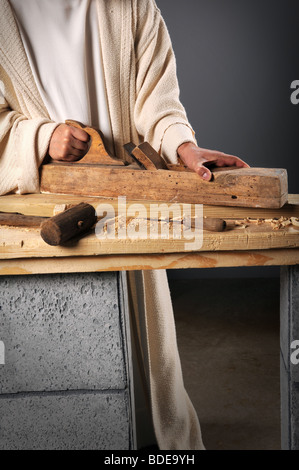 Jesus the carpenter working with a wood plane on a bench Stock Photo