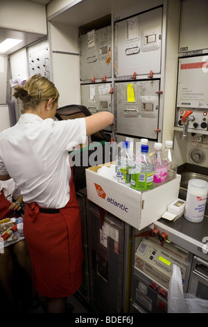 Member of cabin crew with a box of soft drinks on a Virgin Atlantic aircraft during flight to London from Mumbai, India. Stock Photo