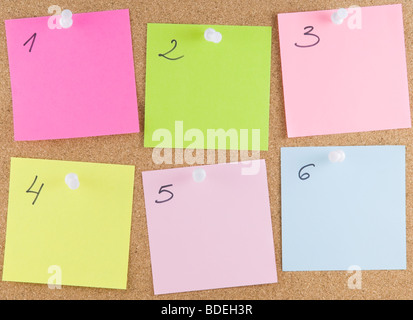 Colourful sticky notes attached to a corkboard Stock Photo