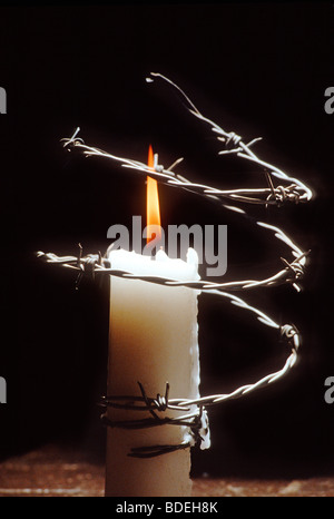 candle encircled in barbed wire Stock Photo