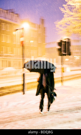 Man with umbrella battles heavy snowfall, London, England, UK, Europe Stock Photo