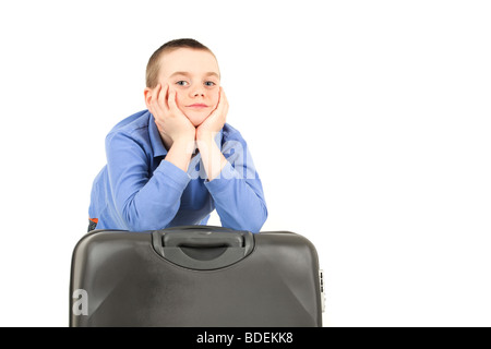 Portrait of young boy leaning on suitcase against white background Stock Photo