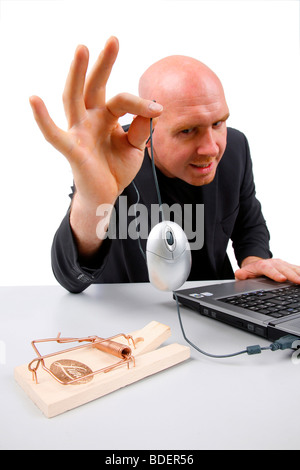 bald headed man holding a computer mouse over mouse trap Stock Photo