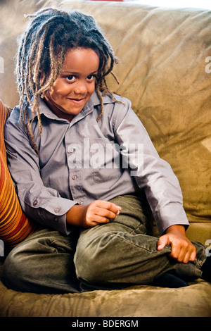 Portrait of mixed race boy sitting on sofa in living room Stock Photo