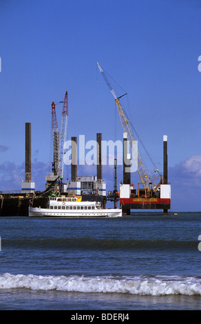 pleasure ship regal lady passing Scarborough harbour and giant cranes on sea platforms constructing sea defences Yorkshire UK Stock Photo