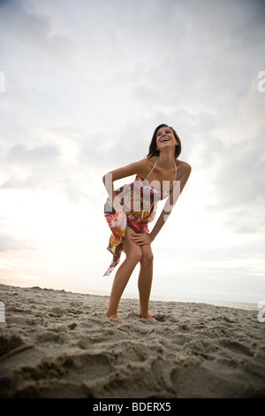Young happy woman in colorful sundress standing on beach Stock Photo