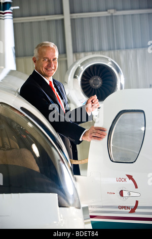 Businessman standing at doorway of corporate jet Stock Photo