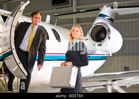 Business executives standing at doorway of corporate jet Stock Photo