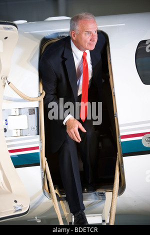 Middle-aged businessman stepping off corporate jet Stock Photo