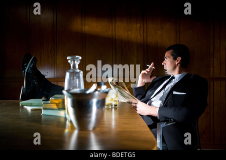 Vintage portrait of businessman smoking with feet up on desk Stock Photo