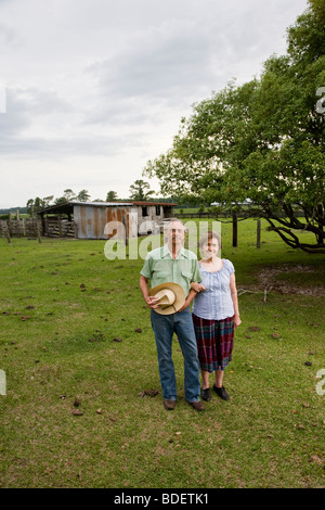 Senior couple standing in field of rural home Stock Photo