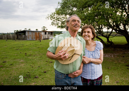 Senior couple standing in field of rural home Stock Photo