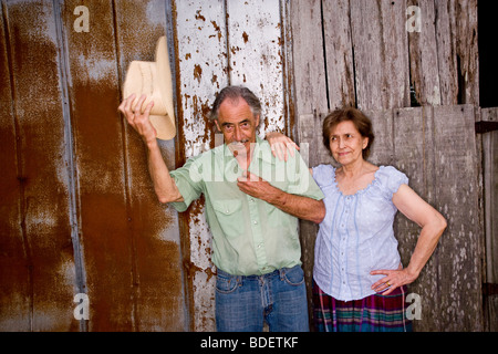 Portrait of senior couple standing near weathered barn wall Stock Photo