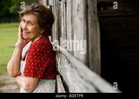 Senior woman standing outside weathered barn Stock Photo