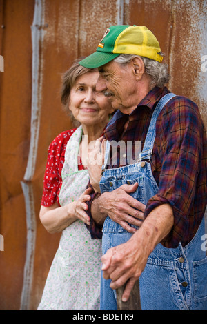 Senior couple standing outside weathered barn Stock Photo