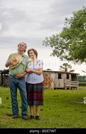 Senior couple standing together outside old farmhouse Stock Photo