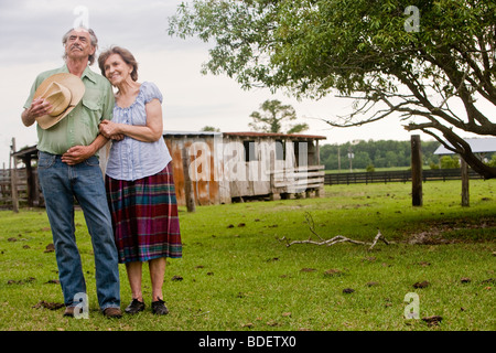 Senior couple standing together outside old farmhouse Stock Photo