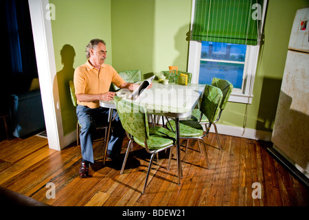 Senior man reading newspaper in kitchen alone Stock Photo