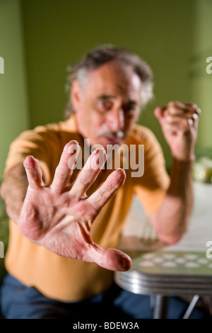 Senior man putting hand out in hesitation, focus on foreground Stock Photo