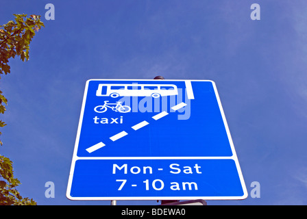 british road traffic sign indicating a bus lane which can also be used by taxis and cyclists and its hours of  operation Stock Photo