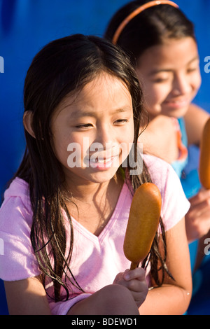 Young girl eating corn dog at water park in summer Stock Photo