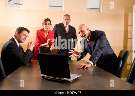 Multi-ethnic business managers looking at laptop in boardroom Stock Photo