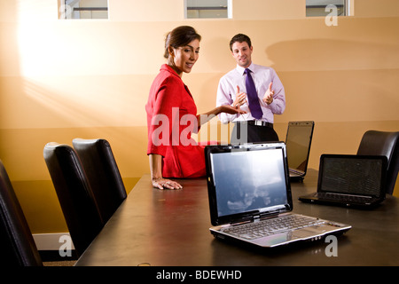 Two businesspeople with laptops in boardroom Stock Photo