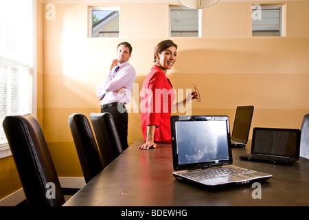 Two businesspeople with laptops in boardroom Stock Photo