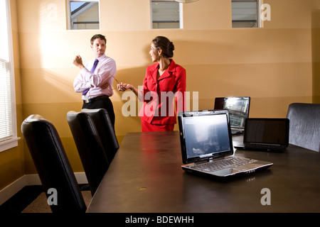 Two businesspeople with laptops in boardroom Stock Photo