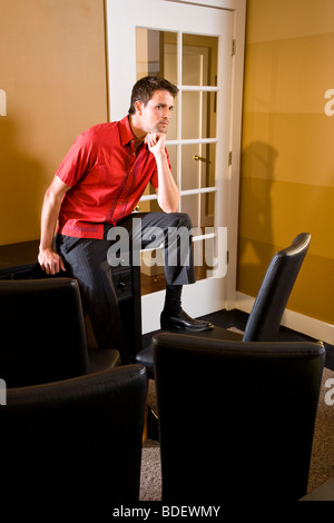 Contemplative mid adult businessman sitting in lounge area Stock Photo