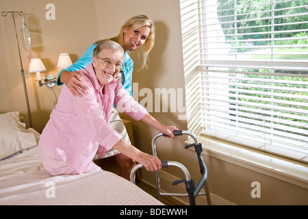 Daughter helping elderly mother use walker Stock Photo