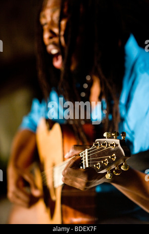 Young Jamaican man with dreadlocks playing guitar on tropical island Stock Photo