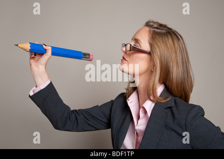 Businesswoman wearing glasses, writing with a giant blue pencil Stock Photo